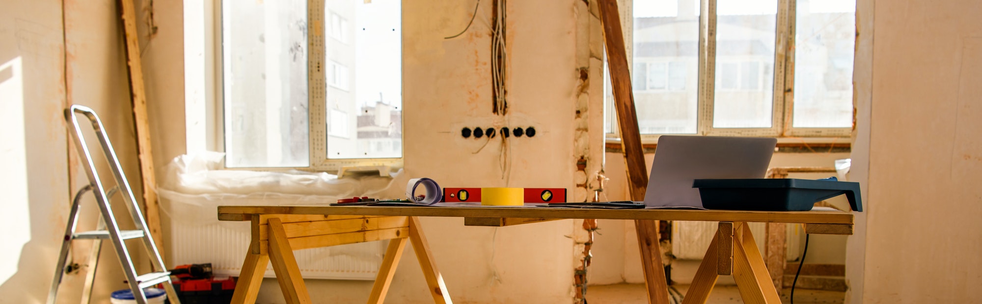 panoramic view of room with tools, ladder and laptop during renovation of home