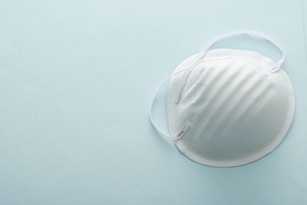 Single surgical face mask on a grey background